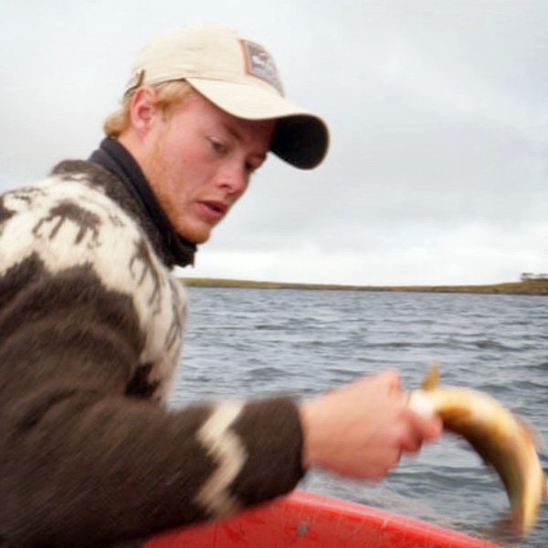 A young man taking fish out of a net.